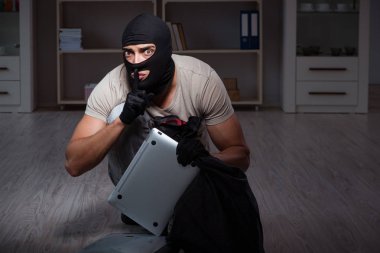 Suç mahallinde kar maskesi takan bir hırsız.