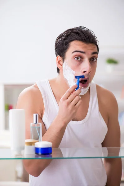 Joven hombre guapo afeitándose temprano en la mañana en casa — Foto de Stock