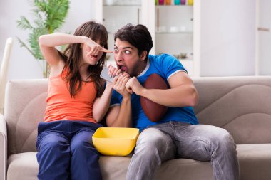 Adam karısıyla Amerikan futbolu seyrediyor.