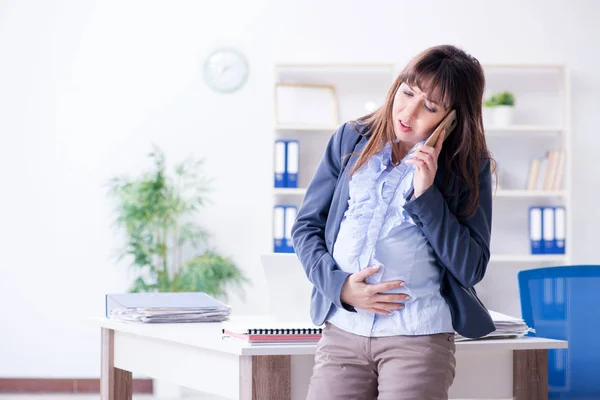 Ofiste çalışmak için çırpınan hamile bir kadın. — Stok fotoğraf