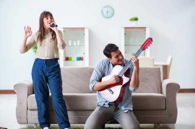 Genç bir aile evde şarkı söylüyor ve müzik çalıyor.