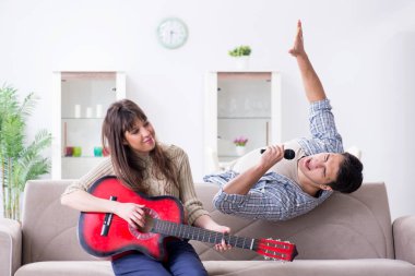 Genç bir aile evde şarkı söylüyor ve müzik çalıyor.