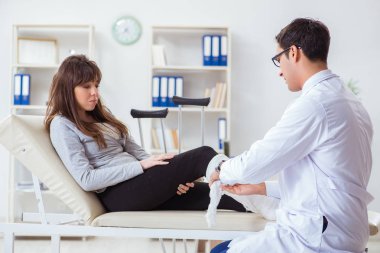 Kırık bacaklı bir hastayı muayene eden doktor.