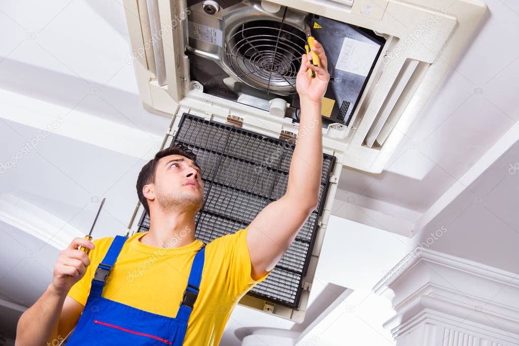 Repairman repairing ceiling air conditioning unit