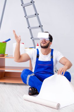 VR gözlüklü, duvar kağıdı yapıştıran bir adam.