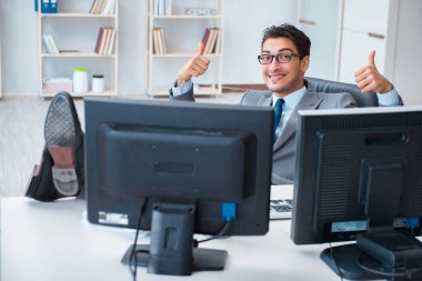 Birçok ekranın önünde oturan bir iş adamı