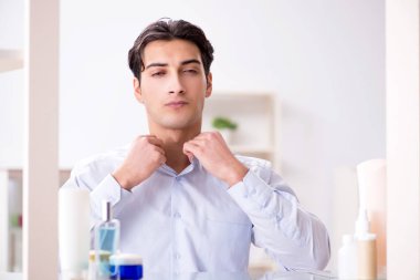 Adam banyoda çalışmak için giyiniyor.