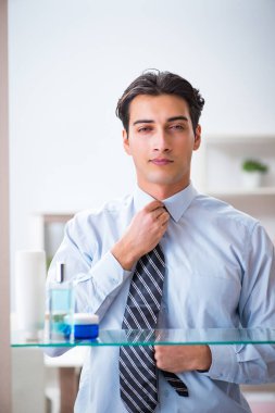 Adam banyoda çalışmak için giyiniyor.