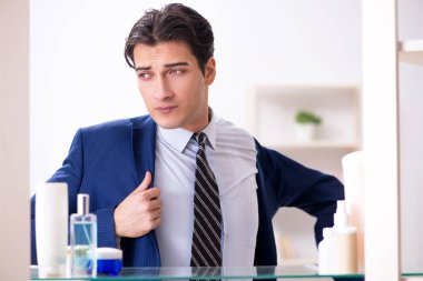 Adam banyoda çalışmak için giyiniyor.