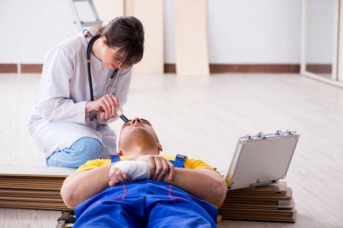 Doktor inşaat alanında yaralı işçiye yardım ediyor.