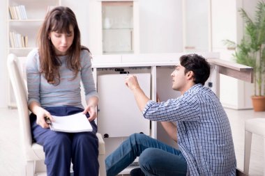 Koca evde kırık masayı onarıyor.