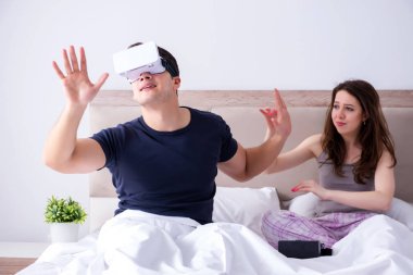 Yatakta sanal gerçeklik gözlüklü eş ve koca.