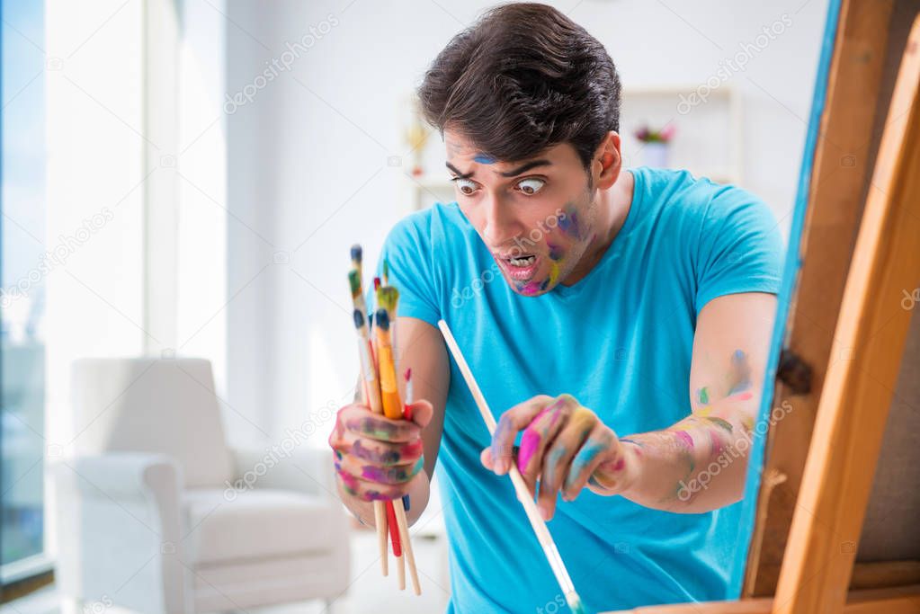 Young funny artist working on new painting in his studio