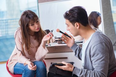 Güzellik salonunda güzel bir kadın için makyaj yapan adam.