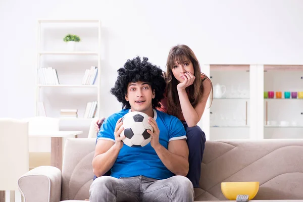 Jovem assistindo futebol com sua esposa em casa — Fotografia de Stock