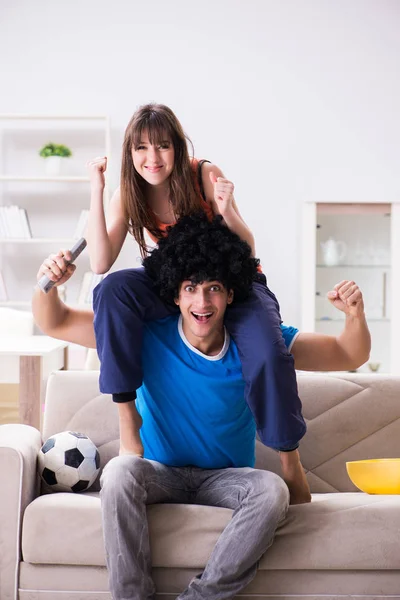 Giovane uomo guardando il calcio con la moglie a casa — Foto Stock