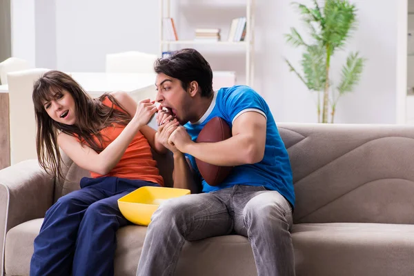 Man watching americal football with his wife — Stock Photo, Image