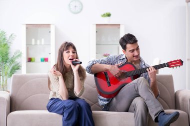 Genç bir aile evde şarkı söylüyor ve müzik çalıyor.