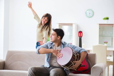 Genç bir aile evde şarkı söylüyor ve müzik çalıyor.
