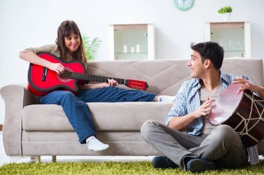 Genç bir aile evde şarkı söylüyor ve müzik çalıyor.