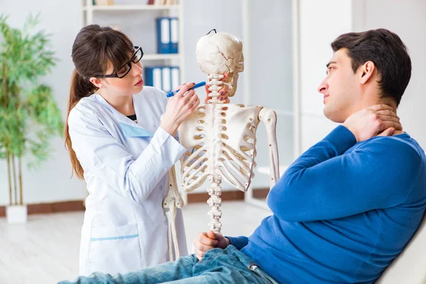 Doctor showing type of injury on skeleton to patient — Stock Photo, Image