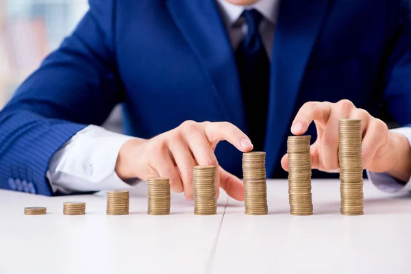 Geschäftsmann mit Stapeln von Münzen im Büro — Stockfoto