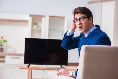 İş adamı ofiste televizyon izliyor.