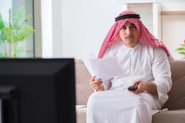 Арабський бізнесмен дивиться телевізор удома. — стокове фото