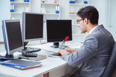 Birçok ekranın önünde oturan bir iş adamı