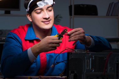 Bilgisayar uzmanı gece geç saatlerde bilgisayarı tamir ediyor.