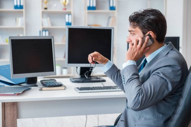 Birçok ekranın önünde oturan bir iş adamı