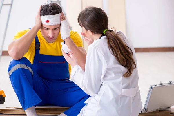 Lavoratore con testa ferita e medico — Foto Stock