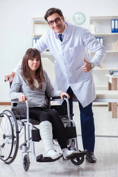 Médico masculino examinando paciente femenino en silla de ruedas —  Fotos de Stock