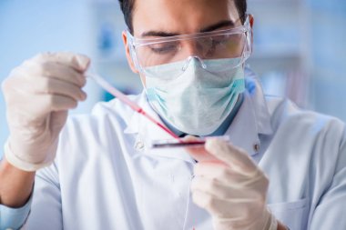 Laboratuvar asistanı hastanede kan örneklerini test ediyor.