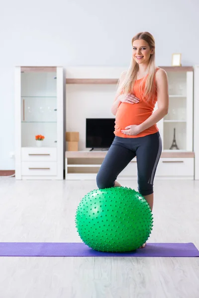 Young woman preparing for birth exercising at home