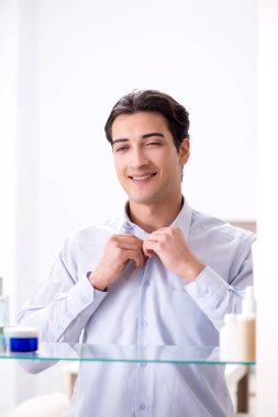 Adam banyoda çalışmak için giyiniyor.