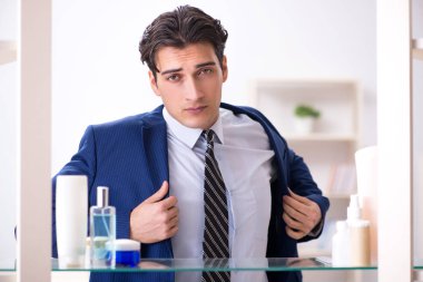 Adam banyoda çalışmak için giyiniyor.