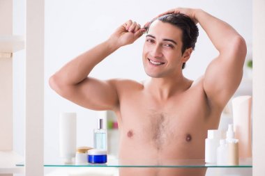 Genç adam banyoda çalışmak için hazırlanıyor.