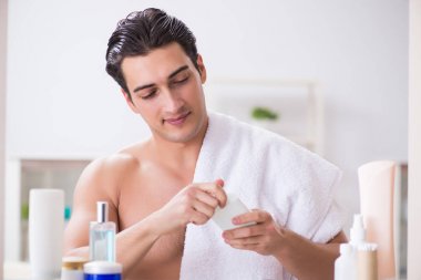 Genç adam banyoda çalışmak için hazırlanıyor.