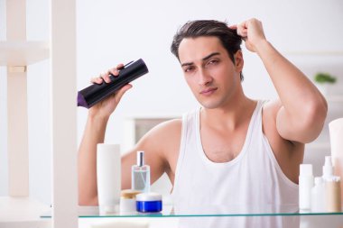 Genç adam sabah saçlarını kurutuyor.