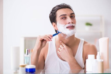 Genç yakışıklı adam sabah erkenden tıraş oluyor.