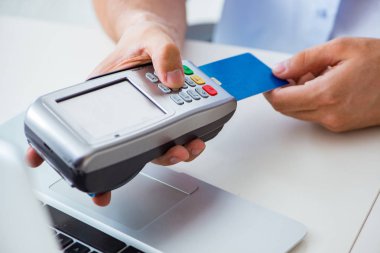 POS terminali ile kredi kartı işlemi yapan adam