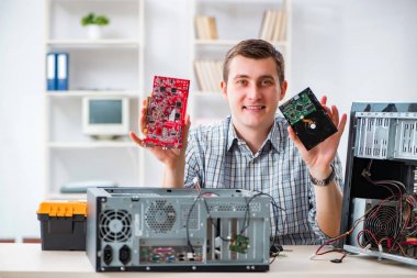 Genç teknisyen atölyede bilgisayar tamir ediyor.