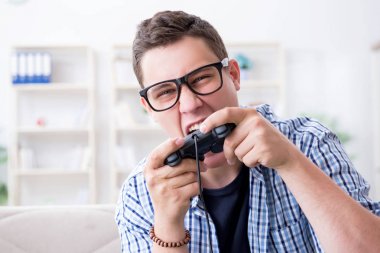 Genç adam evde bilgisayar oyunu oynuyor.