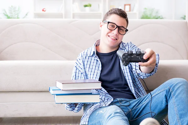 Jeune étudiant essayant d'équilibrer étudier et jouer à des jeux — Photo