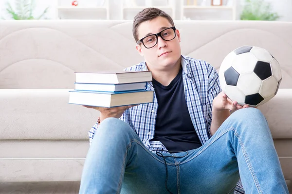 Joven estudiante tratando de equilibrar estudiar y jugar al fútbol — Foto de Stock