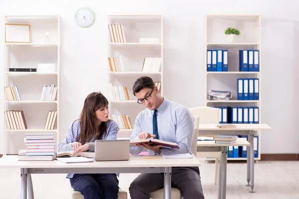 Erkek öğretim görevlisi bayan öğrenciye ders veriyor.