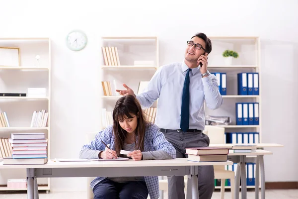 Erkek öğretim görevlisi bayan öğrenciye ders veriyor.