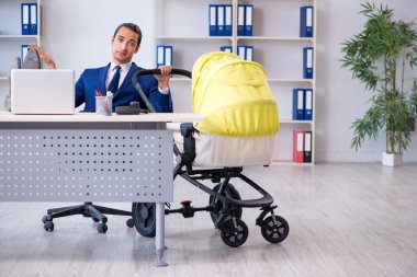 Genç baba ofiste yeni doğan bebeğe bakıyor.