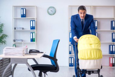 Genç baba ofiste yeni doğan bebeğe bakıyor.